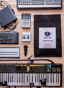 Cup N' Clef Chillwave Kick coffee bag on a table surrounded by musical equipment, blending the world of gourmet coffee with the creativity of music production.