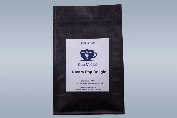 Close-up of Cup N' Clef Dream Pop Delight coffee bag, highlighting the character notes of brown sugar, cocoa, and dried fruit on its label.